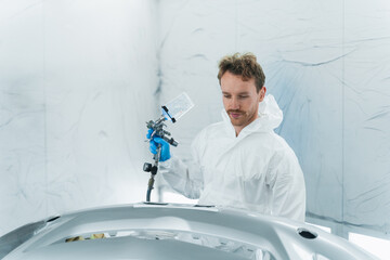 Wall Mural - Car service worker with a paint gun in his hand works in a automobile painting booth