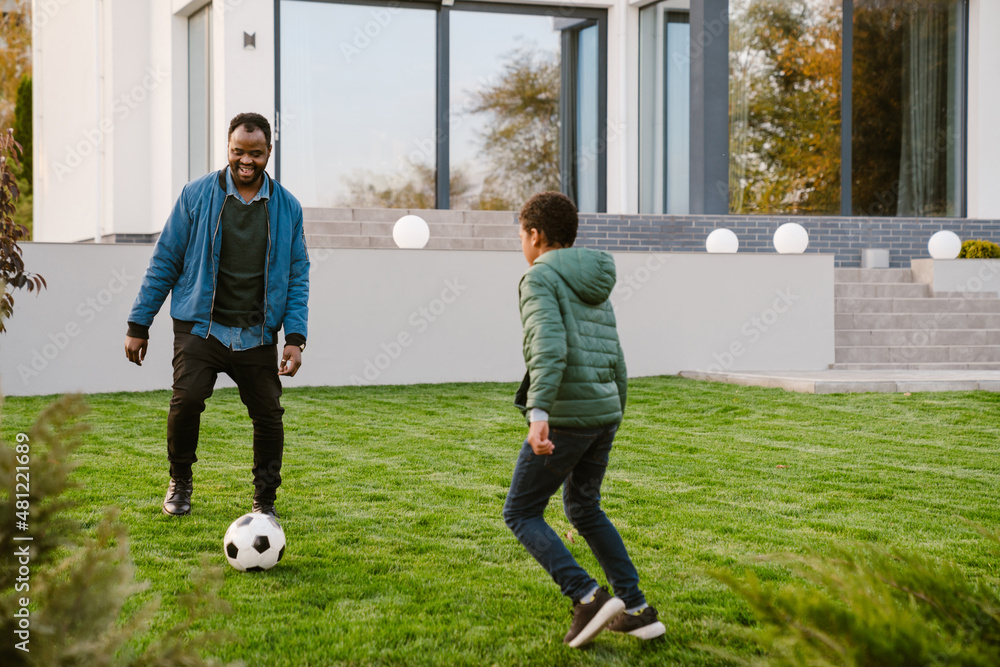 Black man smiling while playing football with his son on backyard Stock ...