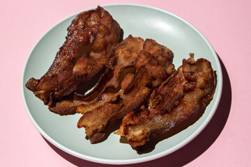 Wall Mural - Fried bacon on a pink background. Bacon fried until crispy. Pig meat.