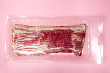 Canvas Print - Vacuum-packed bacon on a pink background. A modern way of storing and selling meat. Pig meat.