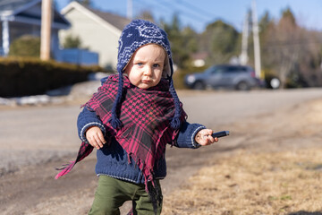 Toddler exploring his local neighborhood on a bright winter day. Portrait of 3 year old child walking alone in the street with blurry background.