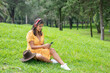 © Edgar1 BJ - Woman sitting on the grass listening to music with headphones while texting with her cell phone