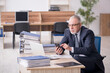 © Elnur - Aged male employee sitting at workplace