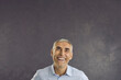 © Studio Romantic - Overjoyed middle-aged man on black studio background look up laugh triumph with good deal promotion or sale discount. Smiling mature male think of offer, consider advertisement. Copy space.