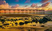 Sunset On The Coast Of Saltburn At Dawn With Pier And Rocks In Foreground