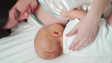 Wall Mural - breastfeeding. mother in a bathrobe feeds the baby with breast milk lying in bed