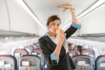 female stewardess demonstrating how to use oxygen mask in plane