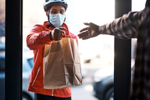 We've Got You Covered During Lockdown. Shot Of A Masked Man Delivering A Food Package.