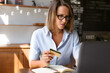 © ksenija1803z - portrait of woman sitting at table works with laptop and pay bank card in her hand
