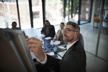 Wall Mural - Just making a little change here. High angle shot of a mature businessman explaining work related stuff during a presentation to work colleagues in a boardroom.