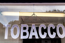 Sign Neon Text Word Hanging On Storefront Glass Window Entrance To Store For Tobacco Cigarettes Cigar Shop During Day Concept Background