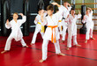 © JackF - Group of girls and boys in kimono doing kata with their trainer in gym.