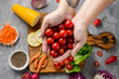 © Patricia Palacio - woman's hand with cherry tomatoes with wooden board with fresh, eco, organic vegetables on gray background