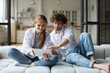 Young couple with digital tablet on cozy sofa, online shopping together at home