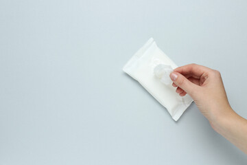 Wall Mural - Woman taking wet wipe from pack on light background, top view. Space for text