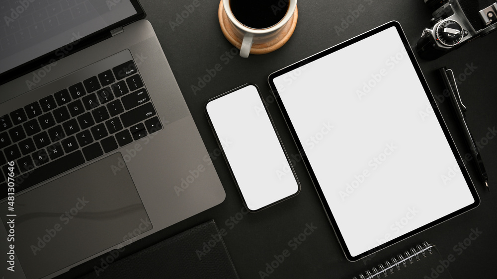 Modern dark workspace with laptop computer, smartphone and digital tablet mockup