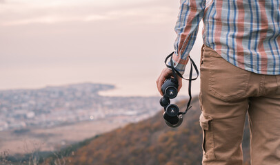 Wall Mural - The unrecognizable traveler stands with binoculars and enjoys nature.