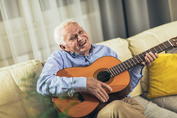 Senior man playing guitar in the living room