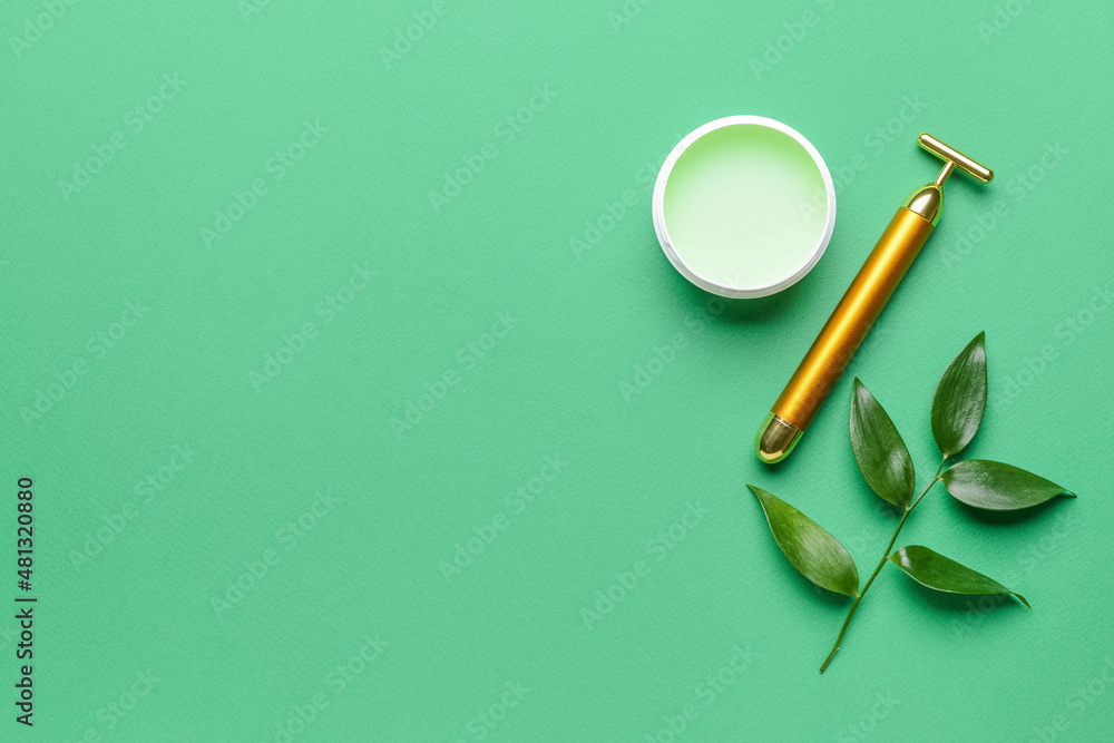 Face massage roller with cosmetic cream on color background