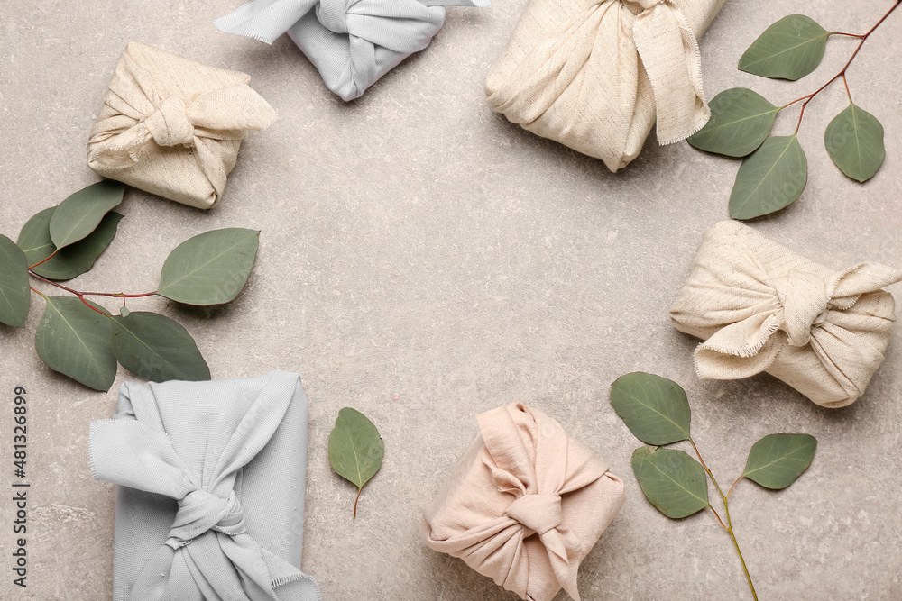Frame made of gift boxes wrapped in fabric and eucalyptus branches on light background