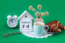 Calendar For February 14: A Decorative House With The Name Of The Month In English, The Number 14, Homemade Cakes, A Cup Of Tea, A Bouquet Of Dried Flowers On An Openwork White Napkin, An Alarm Clock