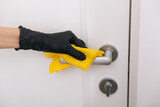 Fototapeta  - Cleaning door handle with yellow wipe in black gloves. Woman hand using towel for cleaning. Disinfection in hospital and public spaces against corona virus.