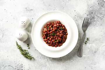 Wall Mural - Stewed red beans with onion and thyme in tomato sauce in a white plate on the kitchen table top view