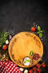 Wall Mural - Food cooking background at black. Cutting board, spices, herbs and vegetables. Top view with copy space.