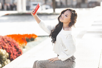 Wall Mural - Beautiful woman outdoors. Pretty lady on urban background. Asian female closeup portrait. Woman making selfie.