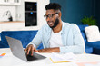 © Vadim Pastuh - Confident concentrated multiracial freelancer guy working on laptop at home office, while sitting at desk and using computer. Brunette man typing on keyboard, looking at screen, enjoying remote work