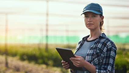 Managing a farm is serious business. Cropped portrait of an attractive young female farmer using a tablet while working on her farm.