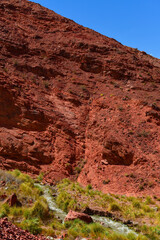 Red rock cliffs and a mountain stream on the road to the Paso de San Francisco mountain pass, Catamarca, Argentina	