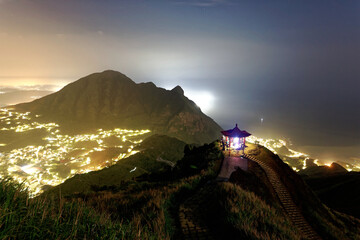 Wall Mural - Aerial scenery of Jiufen at night, a famous tourist town near Keelung on Northeast Coast of Taiwan, with an oriental Gazebo perched on a mountaintop & lights from the village sprawling at the foothill