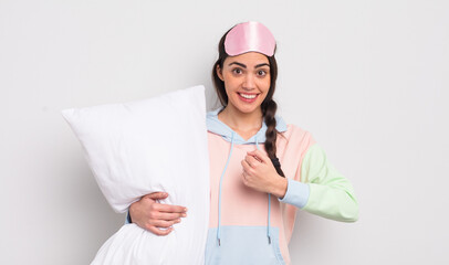 Wall Mural - pretty hispanic woman feeling happy and facing a challenge or celebrating. pajamas and pillow concept