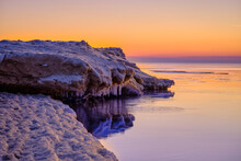 Colorful Beautiful Sunset At Sea In Winter With Snow On The Beach