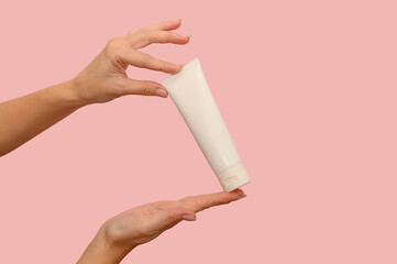 Hand holds a white container with cosmetic cream. For body care.