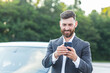 © Liubomir - Cheerful and successful male businessman car salesman uses the phone near the parking lot to sell cars