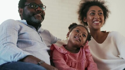 Wall Mural - Laughing African family watching TV and talking at home