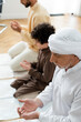 © LIGHTFIELD STUDIOS - Mature man praying with closed eyes near son and muslim child at home.