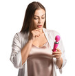 Thoughtful young woman with vibrator on white background