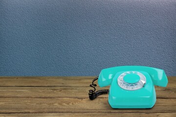 Canvas Print - Retro rotary telephone on table front concrete wall background. Vintage old style