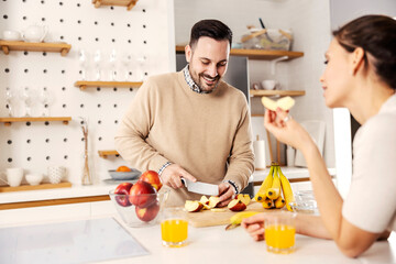 Wall Mural - A man in kitchen preparing healthy snack for his wife at their cozy apartment.