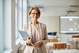 Fototapeta  - Portrait of smiling mature teacher with laptop in the classroom.