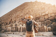 Man tourist walks background of pyramids in Giza Cairo Egypt, sun light
