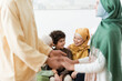© LIGHTFIELD STUDIOS - blurred man holding hands of daughter near happy multiethnic muslim family.