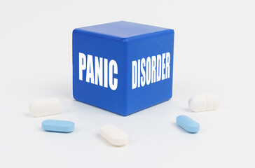 On a white surface are pills and a blue cube that says - Panic Disorder