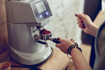  Young woman barista using coffee machine at work