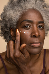 Wall Mural - Studio portrait of senior woman applying eye cream