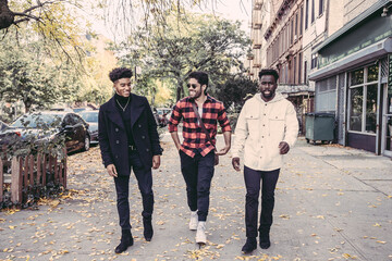 USA, Pennsylvania, Philadelphia, Three male friends walking on sidewalk