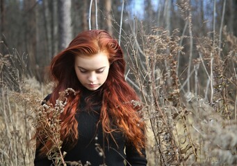 Wall Mural - Young woman with red hair in a field beauty pretty cute face one person nature forest grass nature smile fun happy summer warm outdoors portrait lifestyle